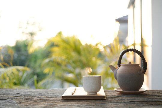 Vintage tea pot and tea cup and notebook, cozy balcony workspace