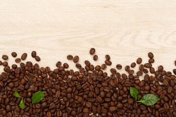 Roasted coffee beans with leaves on wooden background,top view