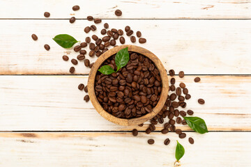 Roasted coffee beans with leaves on wooden background,top view