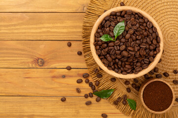 Roasted coffee beans with leaves on wooden background,top view