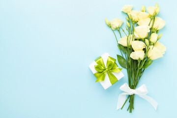 Gift box with beautiful bouquet on color background, top view