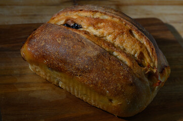 Bakery delight features rustic loaf with golden crust and dark berry speckles on wooden backdrop