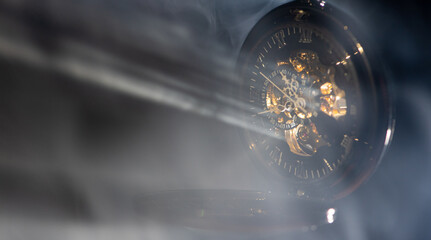 Antique clock, a beautiful antique clock being pierced by rays of light highlighted by smoke, selective focus.