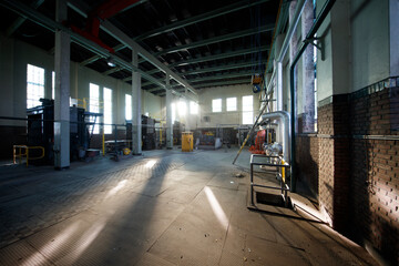 Industrial workspace with natural light highlighting machinery and equipment in a large, empty...