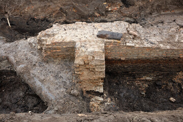 Excavation of ancient city walls revealing historical remains in urban setting
