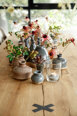 Vases filled with colorful flowers on a rustic wooden table in a cozy indoor setting showcasing natural beauty