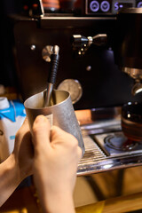The skilled barista meticulously steaming milk to create beautiful espresso art for customers