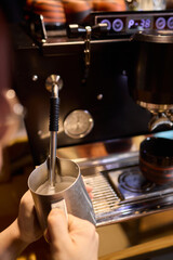 The skilled barista meticulously steaming milk to create beautiful espresso art for customers