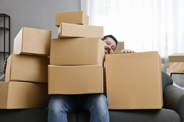 Moving day. Man with cardboard boxes on sofa in his new home