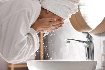 Woman washing her face over sink in bathroom