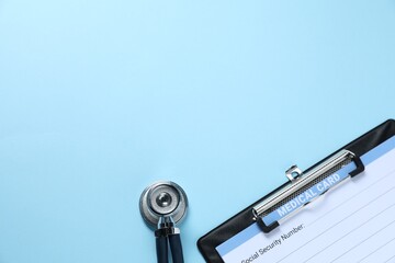 Stethoscope and medical card form on light blue background, top view. Space for text