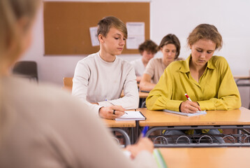 Portrait of teenage school girl and boy sitting together in classroom during lesson in secondary school