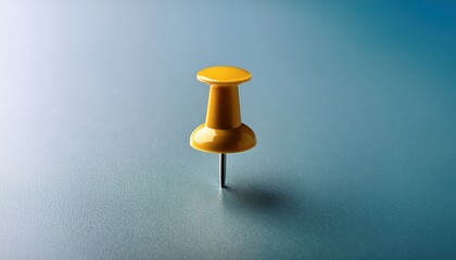 Bright yellow pushpin resting on a smooth blue surface in a minimalist arrangement