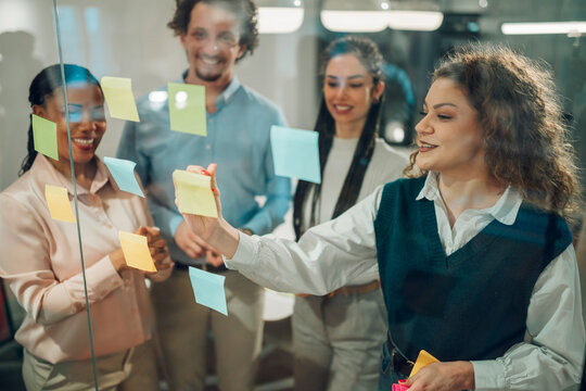 Business team brainstorming and planning using sticky notes on glass wall