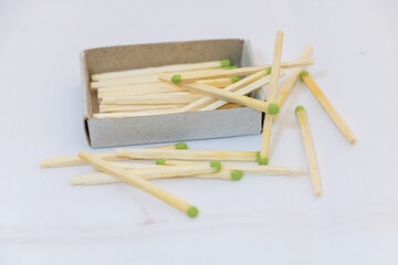 matchsticks in an open box on a white background. The matches have short green tips