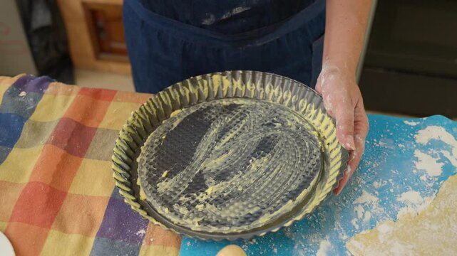 Baker greasing and flouring cake pan in slow motion