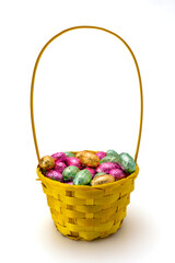 Yellow Wicker Easter Basket with Foil Wrapped Chocolate Eggs Isolated on White Background