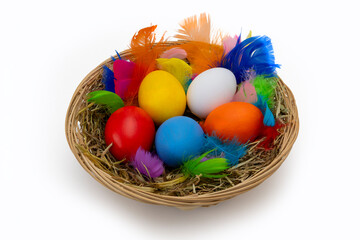 Yellow Wicker Easter Basket with Hand Painted Eggs and Colorful Feathers Isolated on White Background