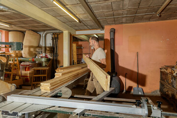  Carpenter handling wooden planks in a traditional woodworking workshop.