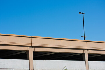 Fototapeta premium Exterior view of upper floors of multi-level parking lot with vertical concrete columns and a black streetlight pole