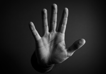 Monochrome hand gesture symbolizing stop or warning in dramatic lighting