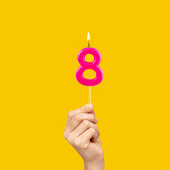 Birthday number 8 - Hand holding fuchsia colored candle