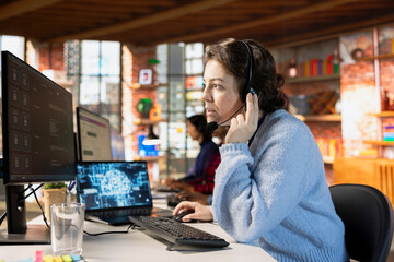 Call center worker wearing audio headset in office using AI to generate call scripts during...