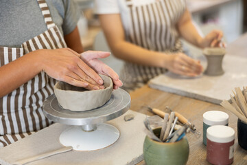Female hands sculpting product from raw clay in ceramic workshop close-up