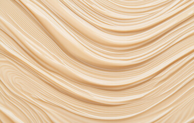 A smooth, uniform beige liquid foundation spread on a white background with visible horizontal waves. Its texture, resembling soft cream or honey, has an almost transparent, glossy appearance in close