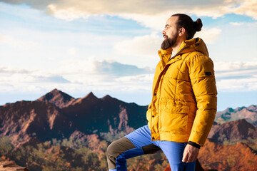 Naklejka premium Determined traveler enjoys the solitude of a mountain summit, where the panoramic view represents adventure and personal growth. Hiker with outdoor gear feeling cold on the windy mountain top.