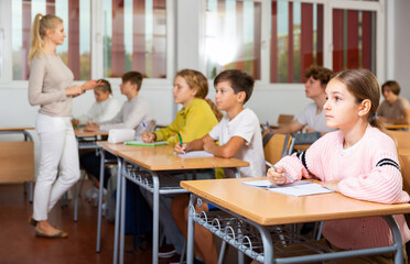 Young boys and girls studying in classroom during lesson in school.