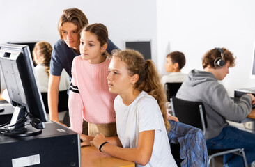 Fototapeta premium Schoolchildren preparing for lessons in the classroom look at the necessary information on the computer