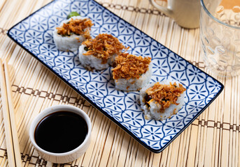 Japanese dish rolls - Karikari roll with crab, avocado, cucumber, fried onion served on plate with wasabi and bowl of soy sauce