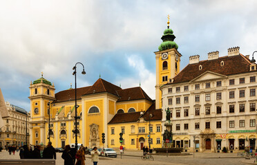 Obraz premium View of medieval Catholic church Schottenkirche and Schottenstift monastery on Freyung square in Vienna on cloudy winter day, Austria