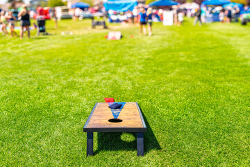 The lawn game of Cornhole, with two boards and fabric bean bags filled with corn at an outdoor family festival on a sunny day.