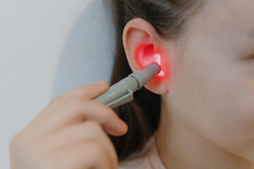 A girl treats her ear with an infrared light device.