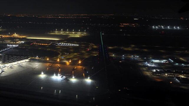 aerial view of airplane taking off at night from King Khalid International Airport in Riyadh, Saudi Arabia, showing ground staff working around airplanes and airport lights illuminating the scene