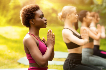 Yoga for inner balance. Group of diverse women meditating at park, copy space