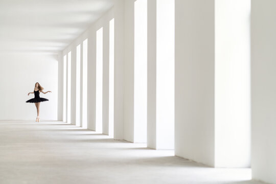 Ballet dancer posing inside light empty space