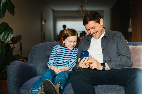 Father and daughter smiling at smartphone