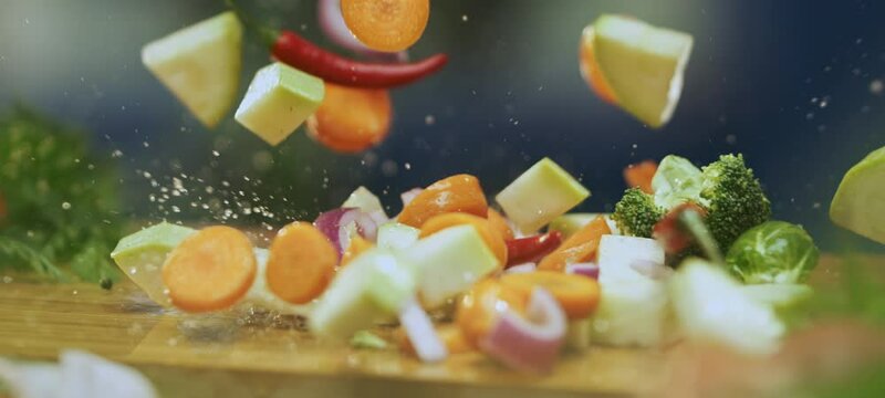 Slow-motion close-up shot of mix vegetables falling on chopping board and they are bouncing on kitchen table