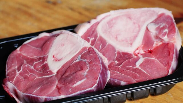 Fresh beef ossobuco steak with salt, spices and herbs on textured background, bones. 