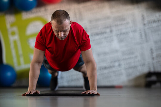 A muscular man performing push ups in the gym, showcasing strength, endurance, and dedication to his fitness routine.