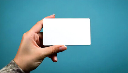 Fototapeta premium 空白の白いカードを持つ手。銀行カード、IDカード、クレジットカードなどの手のポージング素材に最適です。Hand holding blank white card. Perfect for hand posing elements like bank card, ID card, credit card, etc.