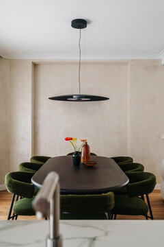 Dining room with a long dark table surrounded by green chairs