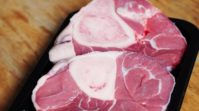 Fresh beef ossobuco steak with salt, spices and herbs on textured background, bones. 