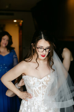 Bridesmaids Help Bride Put on Wedding Dress