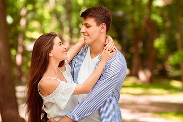 Fototapeta premium Young married couple embracing each other outside on warm summer day, blank space