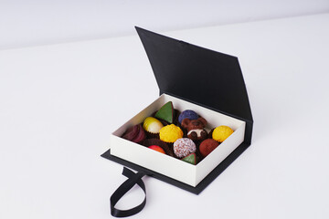 Luxury assorted chocolates and truffles in an elegant black gift box with copy space on white background  
