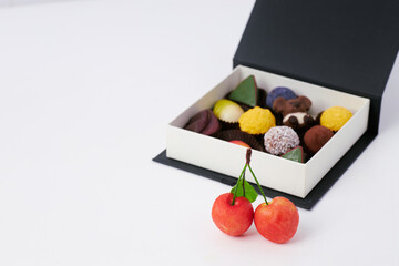 Luxury assorted chocolates and truffles in an elegant black gift box with copy space on white background  
